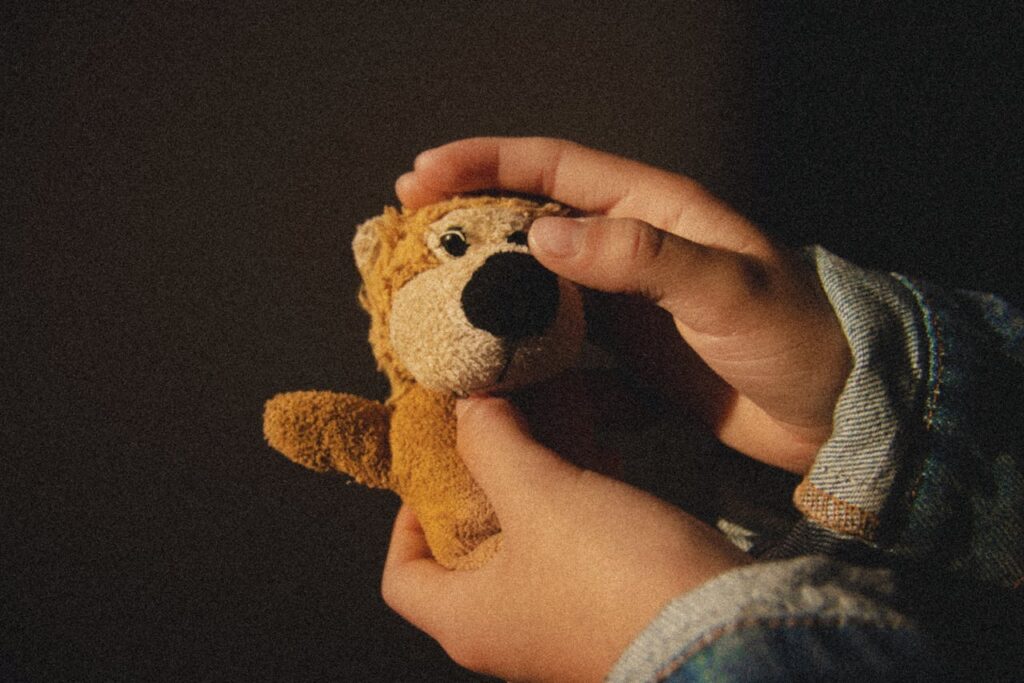 Warm, cozy atmosphere with hands cradling a small plush toy lion in soft light.