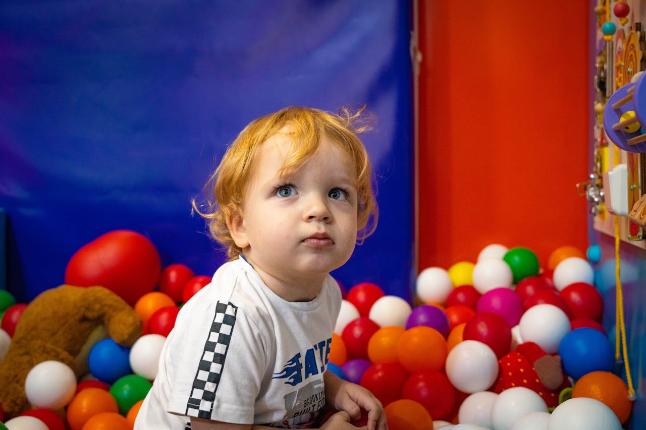 services-02 Adorable toddler exploring a vibrant indoor ball pit. Ideal for playful and family-themed content.