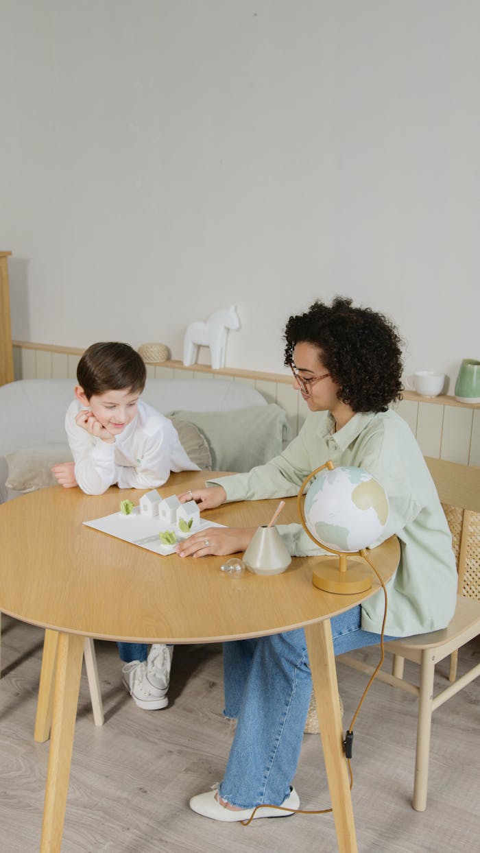 services-01 A child learns geography in a home setting with a teacher, emphasizing interactive education.